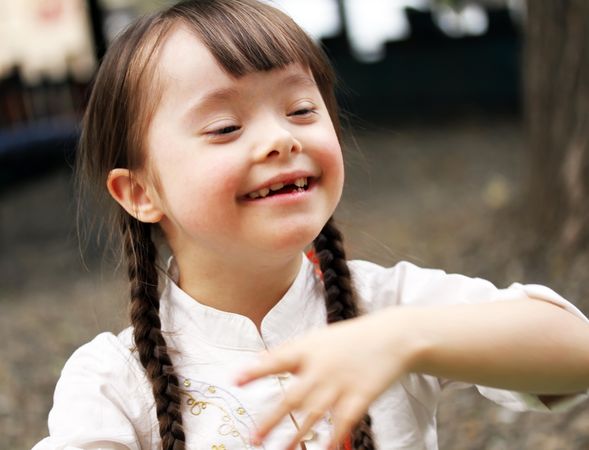 Portrait of happy girl with Down syndrome outside