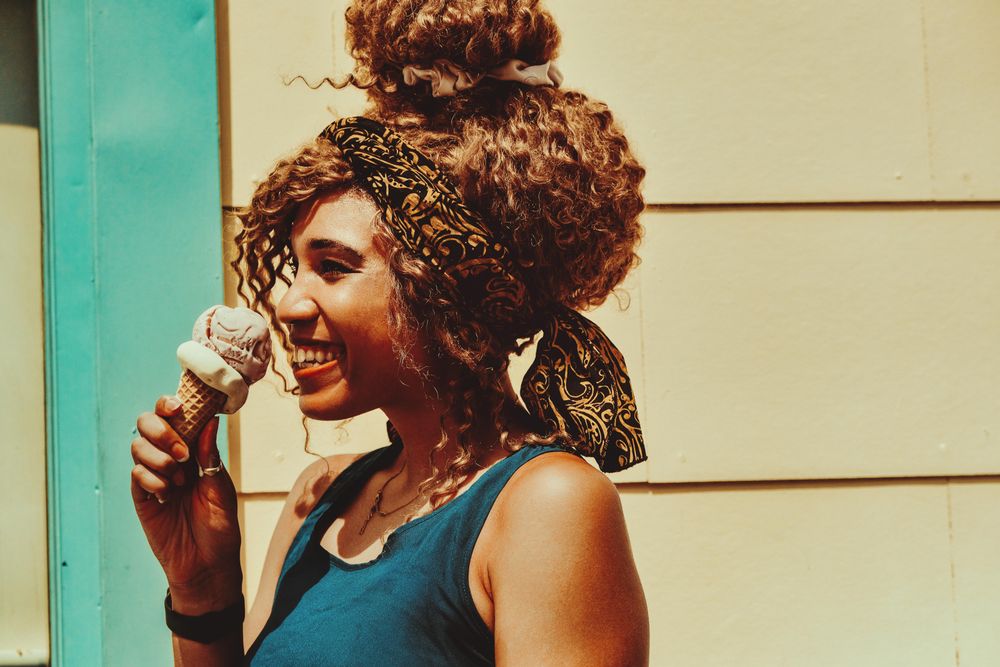 Smiling Black female enjoying an ice cream cone in the sun, copy space