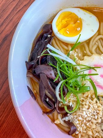 Japanese ramen with egg, mushrooms, sesame, and green onions in broth