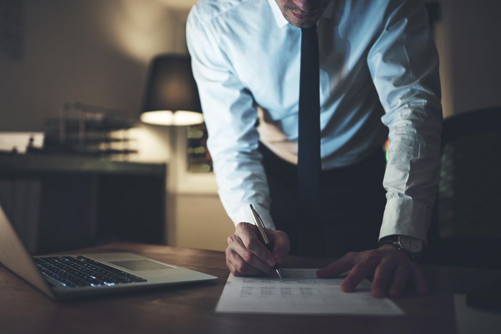 Man signing documents while standing over desk