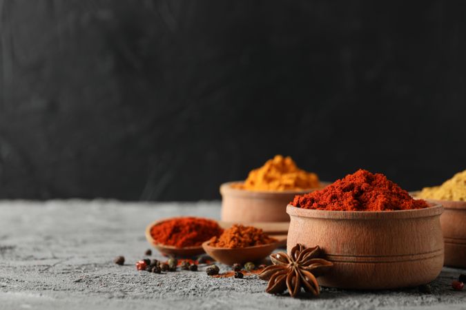 Side view of bowls of spices and garlic bulb, copy space