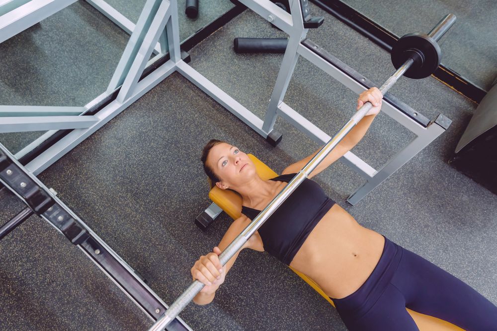 Top view of woman doing bench press in gym