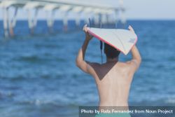 Mid body shot of male surfer looking out to the ocean with board on head 0JLLw4