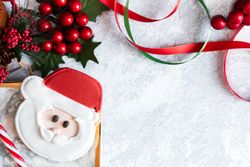 Santa Cookie on a grey backdrop with Christmas decorations.