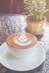 Closeup of cup with hot latte art on glass table