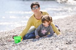 Woman and little girl playing on a rocky beach
