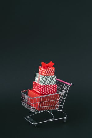 Shopping cart with several wrapped presents on dark background