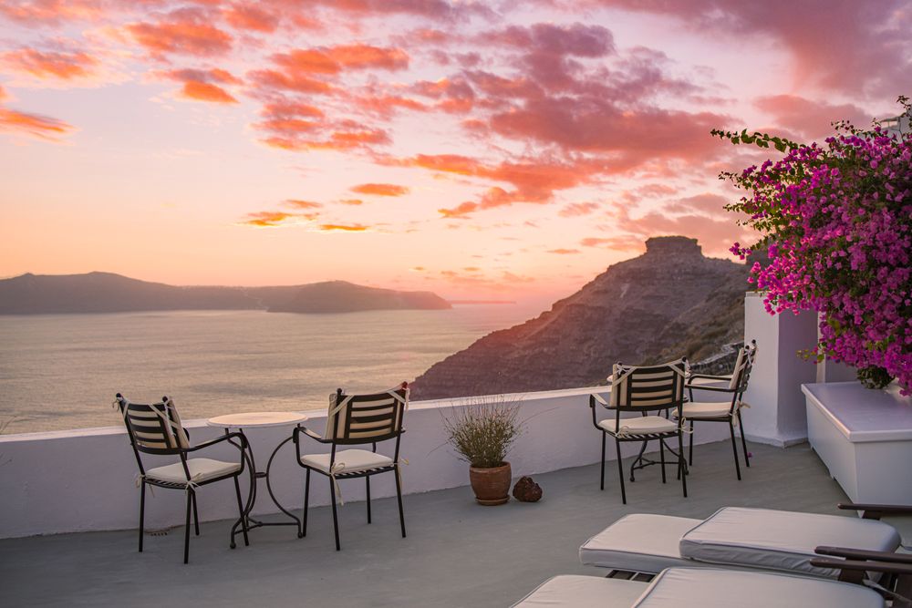 Patio overlooking the sea with three open chairs and two lounge chairs