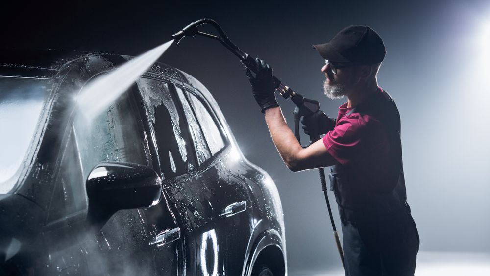 Brand New Electric Vehicle from a Production Line is Being Cleaned with a Water High Pressure Cleaner.