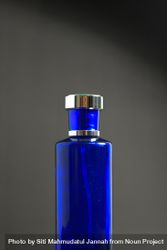 Blue perfume bottle on grey background with copy space 0PjnXO
