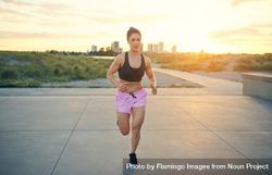 Fit woman running towards camera with skyline in background 5QONNb