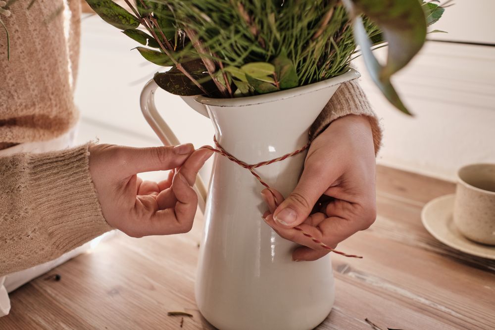 Anonymous florist putting rope around vase
