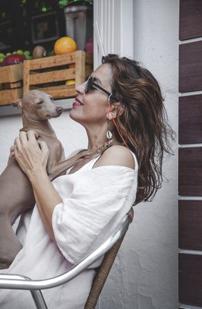 Woman kissing greyhound while relaxing on street
