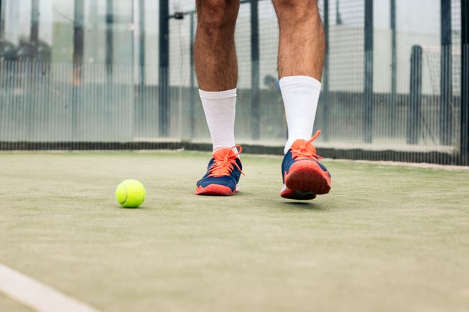 Paddle tennis player close-up photo of the sports shoes and the ball