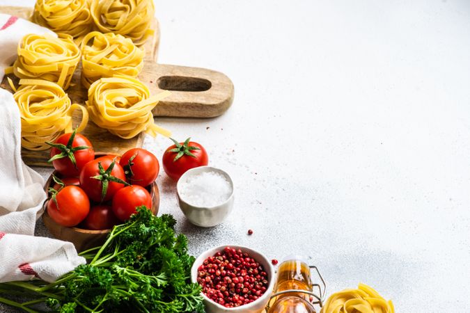 Raw Fettuccine pasta and fresh vegetables on counter with copy space