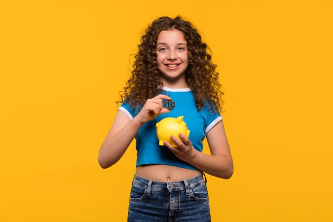 Girl holding Bitcoin and piggy bank