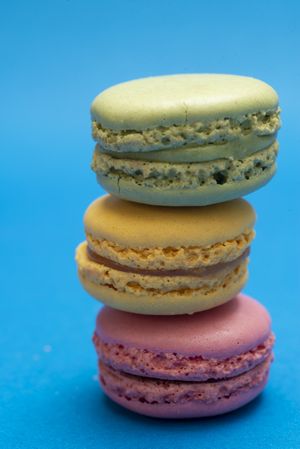Side view of stack of three French pastel macaroons on a blue table
