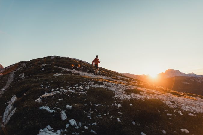 Man walking on shrubland at sunset