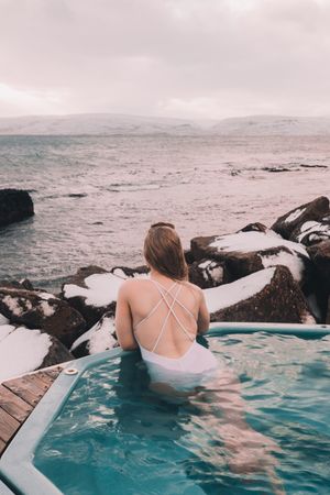 Woman sitting in pool near stones