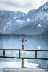 Woman on a bridge enjoying the view of the Alps with arms outstretched 4jMP95