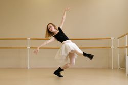 Ballerina in shoes and tutu, extending arm gracefully