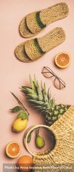 Sandals, glasses, pineapple and fruits in wicker bag, on pink background, vertical composition 5kgOW5