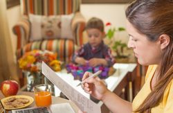 Pregnant mother working in home office with son