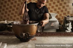 Black male chef using large whisk in steel bowl with melted chocolate 0LMGg5