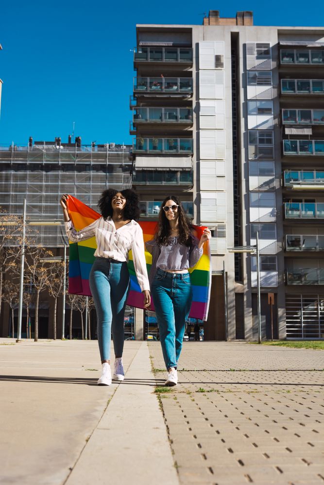 Female couple with rainbow flag walking in city