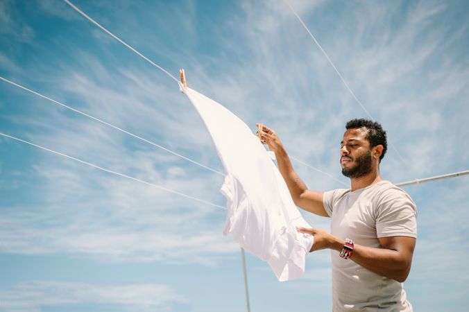 Diligent man hanging t-shirt on rope