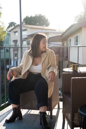 Full length shot of young woman sitting on chair on a patio
