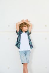Stylish boy in trendy outfit against wall