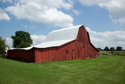 Large red wooden barn with fresh cut grass lawn in rural Alabama O48gJ5
