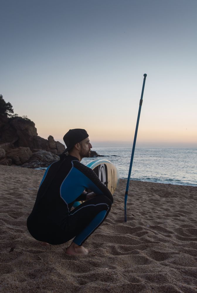 Man practicing paddle surfing with neoprene in a sunrise
