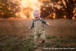 Boy smiling and standing on grass field during sunset 5RLG1b