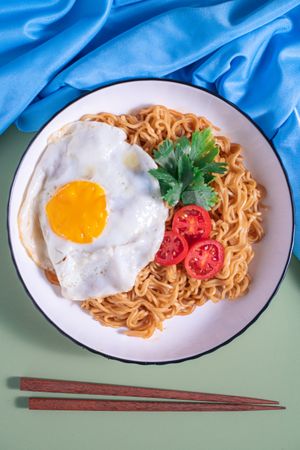 A plate of noodles with an egg and tomato on top
