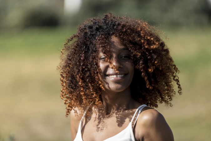 Portrait of curly haired female pictured outside in park