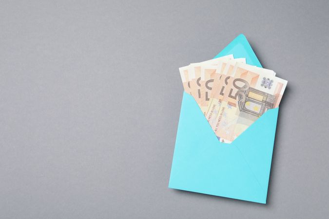 Money in a blue envelope on a gray background.