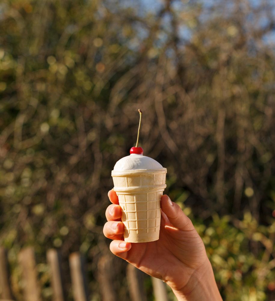 Hand holding ice cream cold topped with cherry