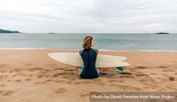 Back of female sitting on the shore with surfboard gazing at the ocean 0PVXa4