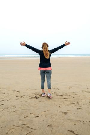Young woman watching the sea with hands up