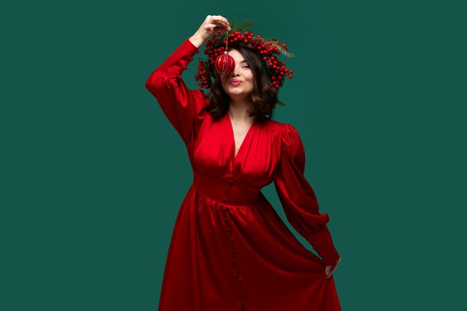 Playful woman holding Christmas ornament above her face.