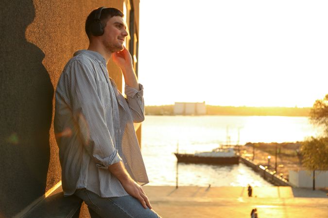 Young man in headphones listen music. Amazing sunset