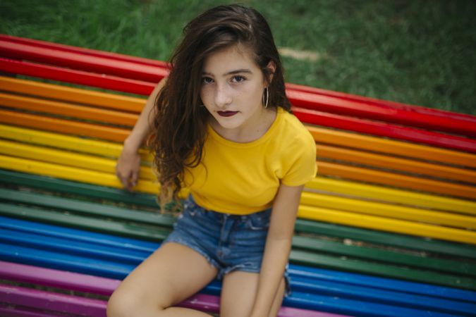 Cheerful woman sitting on rainbow bench