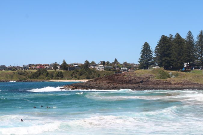 Coastal view of surfers enjoying warm waters in a sunny beach setting during daytime in a scenic location