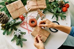 Crop person tying bow on Christmas present on decorated table