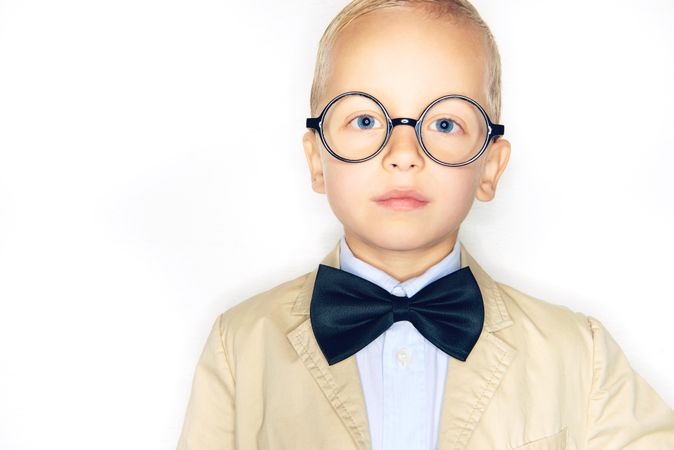 Unsmiling blond boy in glasses with bow tie