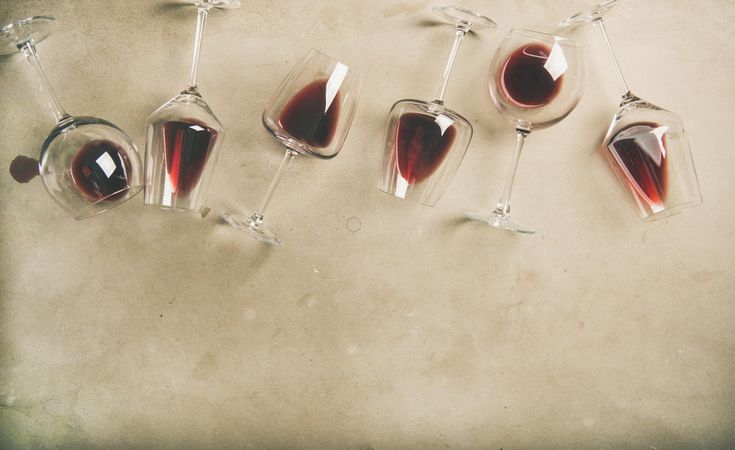Glasses of red wine glasses laying on grey background, horizontal composition with copy space