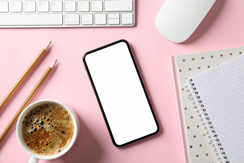 Workplace with phone with empty screen, top view