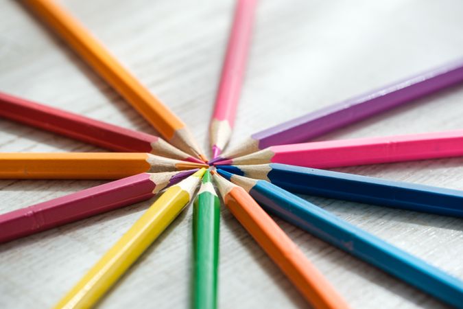 Coloured pencils arranged in a circle on a wooden background